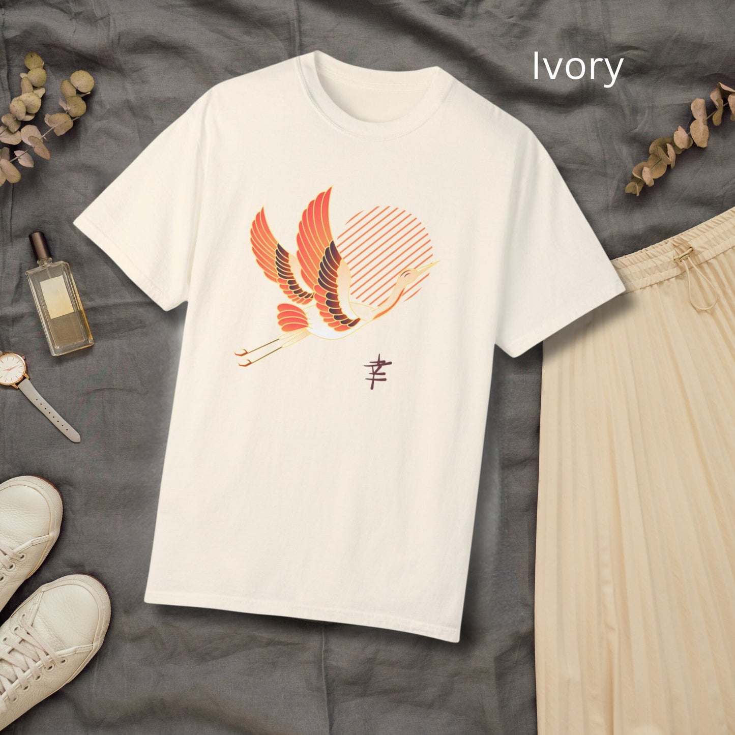 Crew neck cream short sleeve T-shirt with a white and orange japanese crane  flying with legs extended behind it in front of diagonal orange lines arranged to make a sun in the middle. Japanese kanji symbol for happiness below the crane on the left.